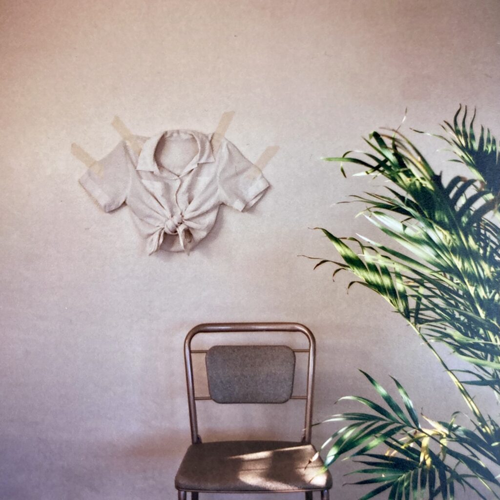 An image of a chair with an article of clothing on the wall.