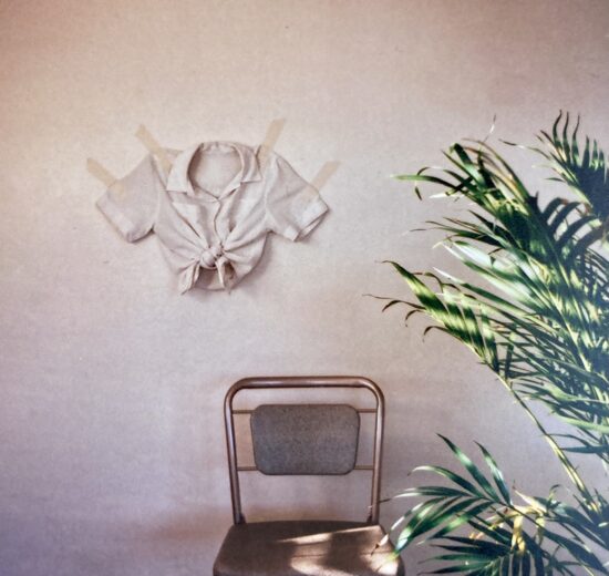 An image of a chair with an article of clothing on the wall.